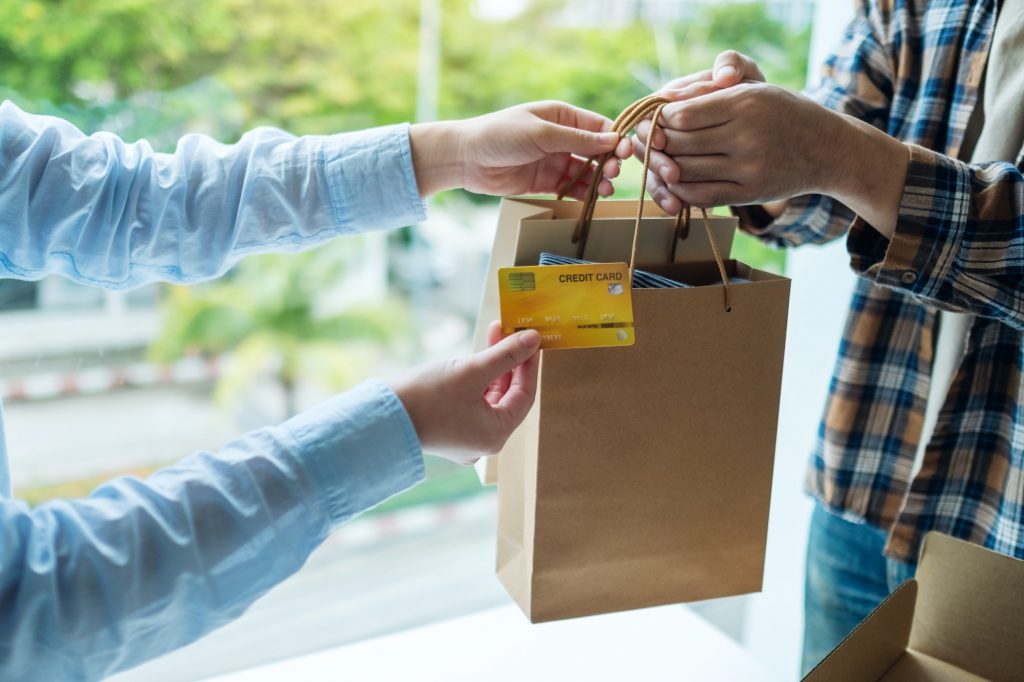 A woman receive shopping bags form delivery man and using a credit card for payment